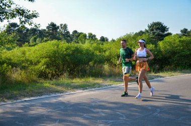 KYIV, UKRAINE - 24 Temmuz 2021: yaz parkında asfalt yolda koşan aktif sporcu erkek ve kadın. Sağlıklı yaşam tarzı kavramı