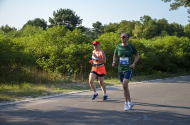 KYIV, UKRAINE - 24 Temmuz 2021: yaz parkında asfalt yolda koşan aktif sporcu erkek ve kadın. Sağlıklı yaşam tarzı kavramı