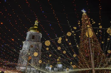 Açık havada ışıklarla süslenmiş Noel ağacı ve Kyiv 'de arka planda Aziz Sophia Katedrali. Yeni Yıl Kutlaması