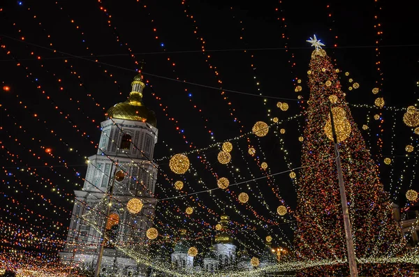 Açık havada ışıklarla süslenmiş Noel ağacı ve Kyiv 'de arka planda Aziz Sophia Katedrali. Yeni Yıl Kutlaması