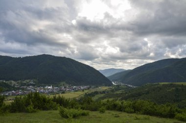 Vadideki tipik dağ köyü ve arka plandaki dağ silsilesiyle güzel bir kır manzarası. Karpatlar, Ukrayna