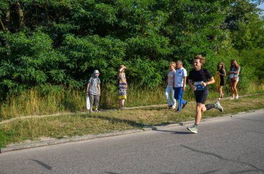 KYIV, UKRAINE - 24 Temmuz 2021: Koşucular açık havada koşuyor. Kentsel alanda yarışan sportif insanlar, sağlıklı yaşam tarzı ve spor kavramları.