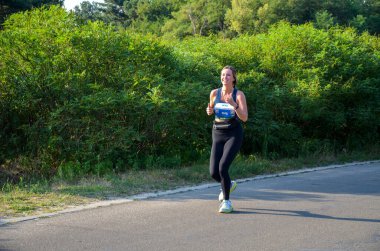 KYIV, UKRAINE - 24 Temmuz 2021: Şehir parkında koşan aktif kız sporcu. Sağlıklı bir yaşam tarzı. Kilo kaybı. Şehir maratonu koşusu.