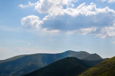 Dağlar, mavi gökyüzünün altında bulutlarla kaplı yeşil çimlerle kaplı. Ukrayna Karpatları 'nda yaz manzarası 