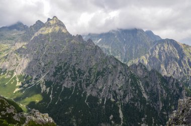 Kayalık dağ sırtı ve bulutların gizlediği keskin tepeleri olan bir manzara. Yüksek Tatras, Slovakya