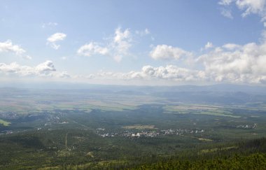 Köyleri, küçük kasabaları, ormanı ve mavi gökyüzünün altındaki tarlaları ve yüksek Tatras Dağları 'ndaki bulutları gösteren vadiye bak. 