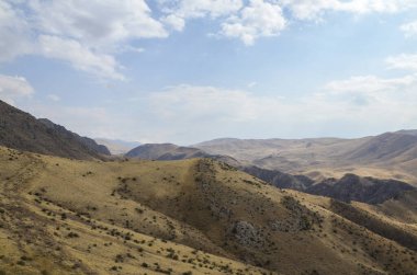Sonbahar Kafkas dağlarının yuvarlak tepeleri ve çıkıntıları çalılarla kaplanmış resim gibi bir manzara. Ermenistan. Doğal duvar kağıdı arkaplanı