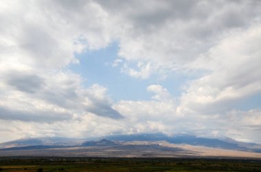 Ararat Dağı 'nın panoramik manzarası Ararat vadisinde yükselen bulutlar ve alçak bulutlarla çarpıcı mavi gökyüzü.