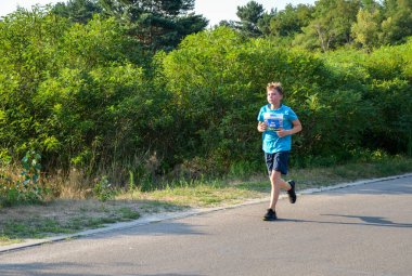 KYIV, UKRAINE - JULY 24, 2021: Athletic young man running in the nature. Dynamic movement. Urban healthy active lifestyle.