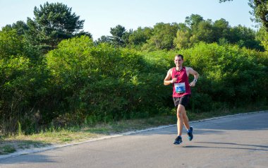 KYIV, UKRAINE - JULY 24, 2021: Athletic young man running in the nature. Dynamic movement. Urban healthy active lifestyle.