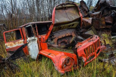 Terk edilmiş eski bir itfaiye aracının kırık kulübesi hurda bir metal yığınının içinde geri dönüşüme hazır yatıyor.