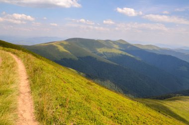 Güneşli bir yaz günü, bulutlu mavi Si 'nin altında dik yeşil çimenli yamaçlar olan dağ sırtından geçen patika. Karpat Dağları, Ukrayna 'nın güzel manzarası