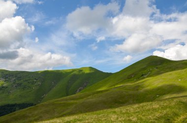 Dağ sırtı manzarası, vadi ve çayır manzarası Karpat dağlarında mavi gökyüzü ve beyaz bulutlar altında