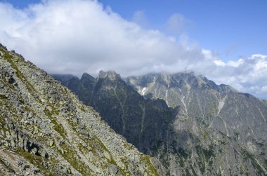 Yüksek Tatra dağlarının kayalık dağ sırtı, mavi gökyüzü ve tepelerdeki bulutlar. Slovakya 'da yürüyüş, yürüyüş ve tırmanma.