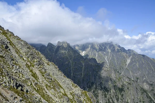 Yüksek Tatra dağlarının kayalık dağ sırtı, mavi gökyüzü ve tepelerdeki bulutlar. Slovakya 'da yürüyüş, yürüyüş ve tırmanma.