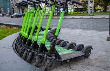 Şehir caddesinde park etmiş elektrikli scooterlar. Kamu kullanımı için Eko-ulaşım kiralama istasyonu