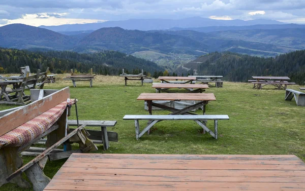 Recreation area with wooden tables for picnic and beautiful autumn panorama of Carpathian Mountains on background