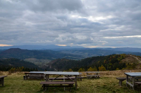 Recreation area with wooden tables for picnic and beautiful autumn panorama of Carpathian Mountains on background