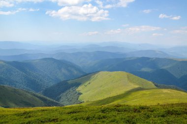 Tepelerde yeşil çayır ve orman olan yaz dağı manzarası mavi gökyüzünün altında bulutlarla. Borzhava Karpatların, Ukrayna 'nın harika seyahat yeri