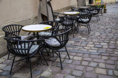Outdoors street cafe with round tables and wicker chairs. Food and recreation