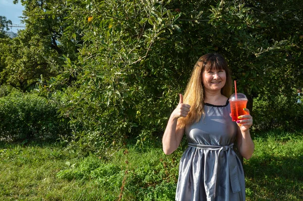 Young smiling girl holding tasty sweet fresh lemonade with ice, amazing relaxing day, tasty drink, outdoor