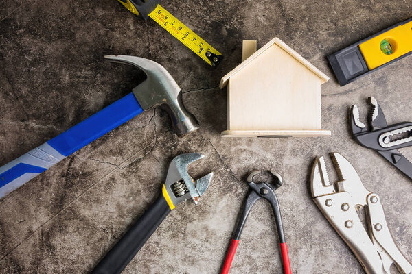 Деревянные белый дом игрушки и строительные инструменты на сером-черном цементном фоне на фоне с копировальным space.Real недвижимости концепции, новый house.Home ремонт концепции