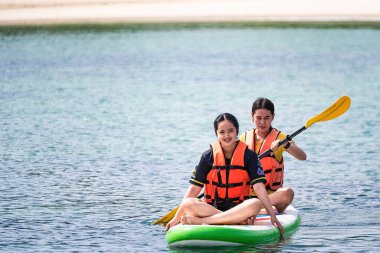 Chon Buri, Tayland - Ekim 02, 2021: Kimliği belirsiz genç bir kadın, Chon Buri, Tayland 'da denizde kürekle yemek tahtasında oturuyor.