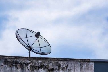 Binanın güvertesinde uydu anteni ve kabarık uzayı olan mavi gökyüzü.