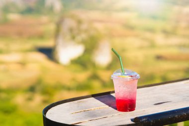 Kırmızı gazoz buzda, plastik bardakta masada..