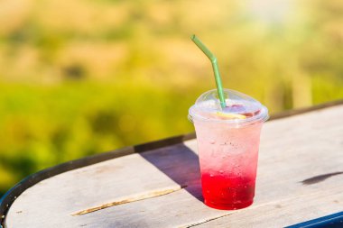 Kırmızı gazoz buzda, plastik bardakta masada..