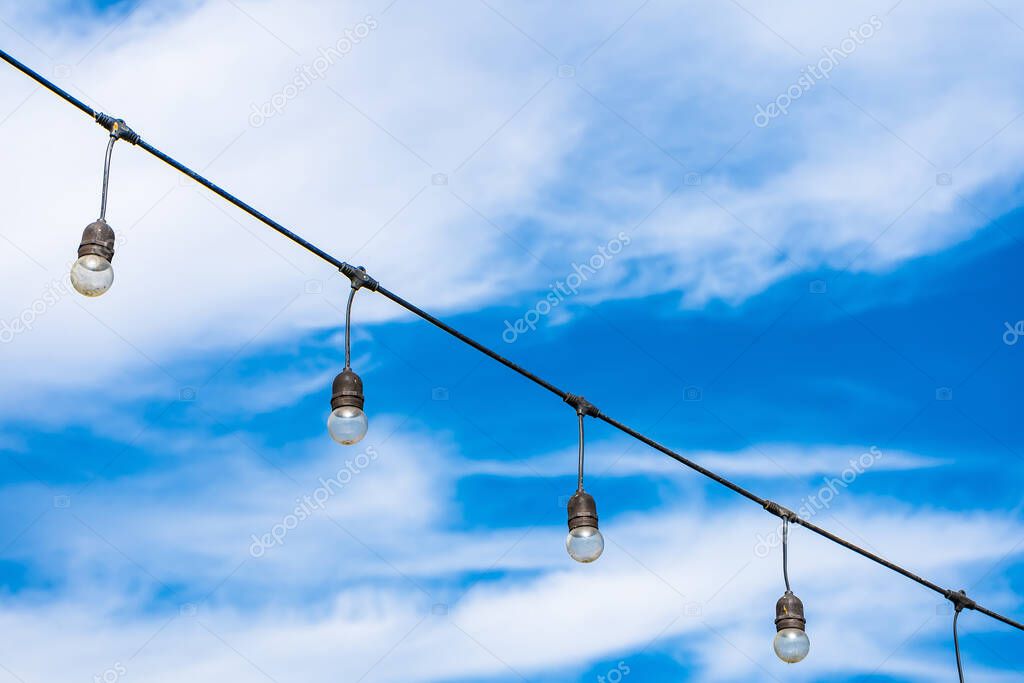 vintage light bulbs hanging at outdoors garden with sunny blue sky