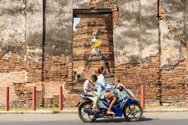Ayutthaya, Tayland - Şubat 05, 2022: Kimliği belirsiz kişilerin hareket bulanık fotoğrafı Ayutthaya, Tayland 'daki terk edilmiş tapınağın önündeki yolda motosiklete biniyorlar