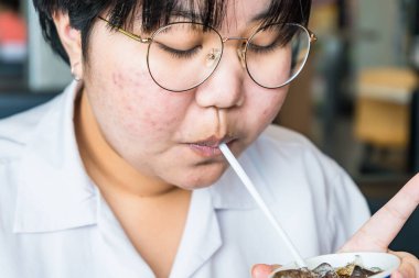 Bangkok, Tayland - 25 Haziran 2021: Kimliği belirsiz Asyalı genç Bangkok, Tayland 'da bir restoranda pipetten su emiyor.