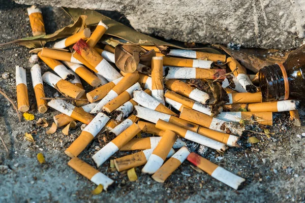 The ashtray at the public smoking area that full of cigarette butts.