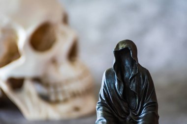 Azrail heykeli oturuyor ve kafatası arka planda..