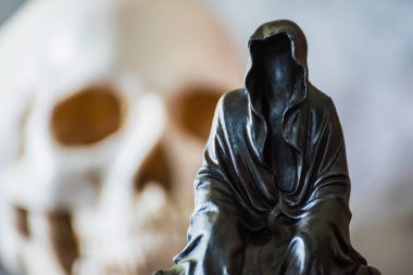 Azrail heykeli oturuyor ve kafatası arka planda..