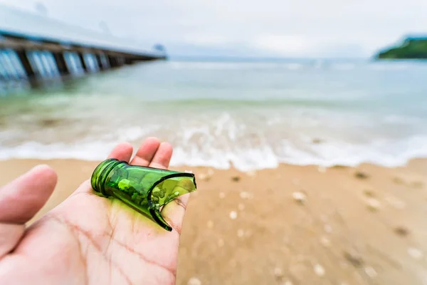 Broken beer bottle in hand on the beach,Concept of pollution control of the seas and oceans