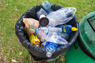 Bangkok, Thailand- August,13, 2022 :Piled up garbage of single use waste food drink containers including single use plastic waste, bottles overflowing garbage bin in a public park.