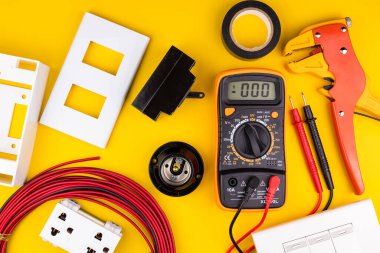 Sarı arka planda farklı elektrikçi malzemeleri var. Metin için alanı olan profesyonel elektrikçi araçlarının arkaplanı. Elektrikçi konsepti ev elektrik tamircisi.