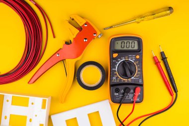Sarı arka planda farklı elektrikçi malzemeleri var. Metin için alanı olan profesyonel elektrikçi araçlarının arkaplanı. Elektrikçi konsepti ev elektrik tamircisi.