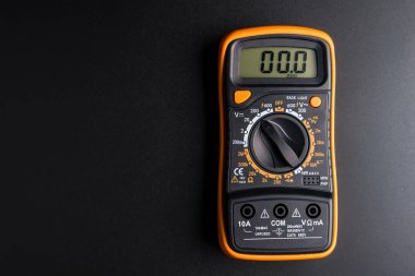 Siyah arka planda sondaları olan sarı dijital çokölçer, çoklu metre elektronik bir ölçüm aletidir..