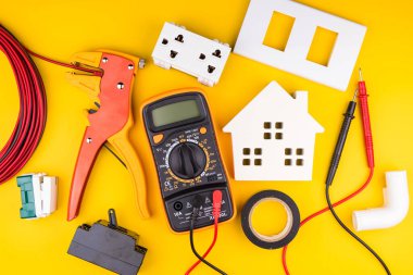 Sarı arka planda farklı elektrikçi malzemeleri var. Metin için alanı olan profesyonel elektrikçi araçlarının arkaplanı. Elektrikçi konsepti ev elektrik tamircisi.