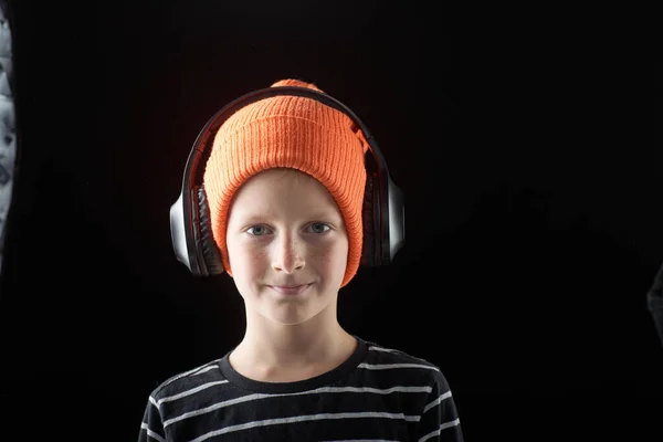 暗い背景にオレンジ色の帽子で10歳の少年の肖像 — ストック写真