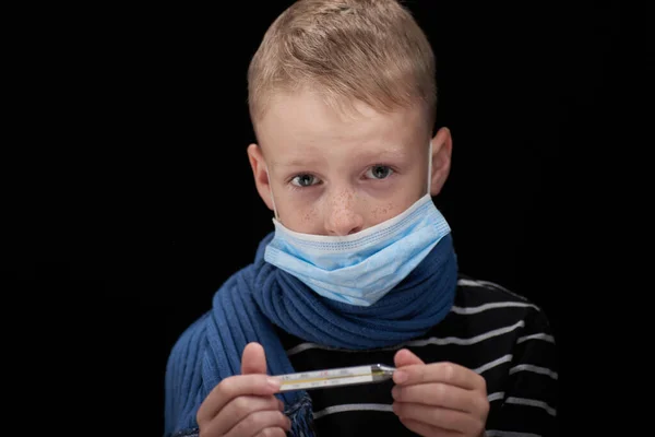 暗い背景に温度計付きのマスクの病気の少年の肖像画 — ストック写真