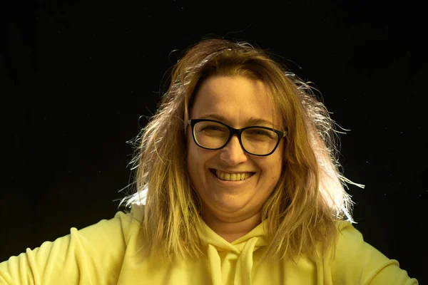Adult woman in glasses with bad hair, on a dark background