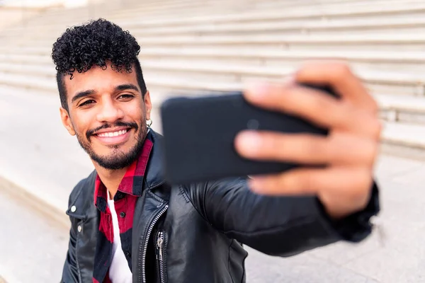 Szczęśliwy Młody Latynos Uśmiecha Się Robiąc Sobie Selfie Swoim Smartfonem — Zdjęcie stockowe