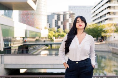 successful businesswoman looking proud at the camera in the financial district of the city, concept of entrepreneur and urban lifestyle, copy space for text