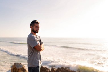 Çekici bir adamın portresi deniz kenarındaki bir uçurumdan gün batımını izliyor, boş zaman kavramı ve rahatlama, metin için kopyalama alanı