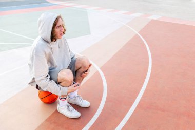 Basketbol antrenmanından sonra sahada oturan beyaz bir adam için sürpriz oldu. Şehir sporu kavramı, metin için kopyalama alanı.