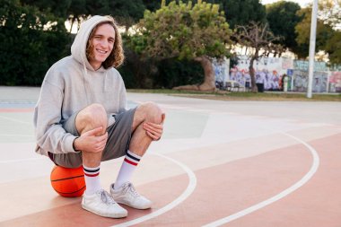 Basketbol antrenmanından sonra sahada oturan gülümseyen beyaz adam, şehir sporu kavramı, metin için kopyalama alanı
